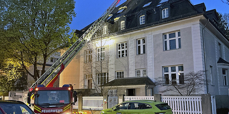 Brandbekämpfung beim Dachstuhlbrand: Gebäudeansicht mit Drehleiter 